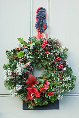 DESIGNER_CAROLYN_MINTY__GLOUCESTERSHIRE__CHRISTMAS_NATURAL_PINE_WREATH_ON_THE_FRONT_DOOR_DRESSED_WIT
