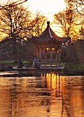 RHS GARDEN WISLEY  SURREY:  EVENING VIEW OF SEVEN ACRES ACROSS THE LAKE TO THE CHINESE PAGODA. WINTER  JANUARY