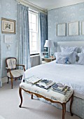 DESIGNER JANE CHURCHILL : MAIN BEDROOM  CHAIR IN ANTIQUE EMBROIDERED LINEN  CURTAIN FABRIC USED AS WALLPAPER  BEDSIDE TABLE BY JANE CHURCHILL TO GIVE EXTRA WIDTH IN LIMITED SPACE