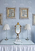 DESIGNER JANE CHURCHILL : DRESSING TABLE IN MAIN BEDROOM WITH SKIRT MADE FROM ANTIQUE SHEET. PAINTINGS ABOVE BY BIANCA SMITH