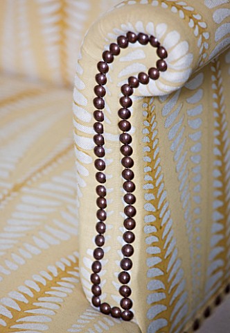 DESIGNER_JANE_CHURCHILL__STUD_DETAIL_ON_ARM_OF_UPHOLSTERED_CHAIR_IN_THE_DRAWING_ROOM