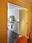DESIGNER JANE CHURCHILL : THE DINING ROOM WITH KITCHEN BEYOND - YELLOW LINEN WALLS   CAMOUFLAGES JIB DOOR LEADING TO KITCHEN