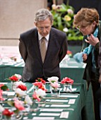 JUDGES LOOKING AT CAMELLIAS AT THE RHS CAMELLIA SHOW IN VINCENT SQUARE  LONDON