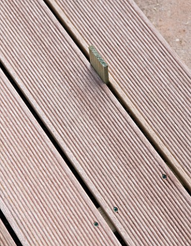 DECK_PROJECT__DEVON__DESIGNER_CLARE_MATTHEWS__USING_A_PIECE_OF_WOOD_TO_MAKE_SURE_DECKING_IS_THE_RIGH