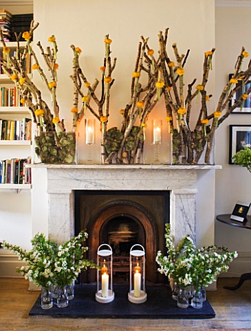 DESIGNER_KALLY_ELLIS__LONDON_FIREPLACE_WITH_DISPLAYS_OF_SPIRAEA_BRANCHES_IN_GLASS_JARS_WITH_HURRICAN