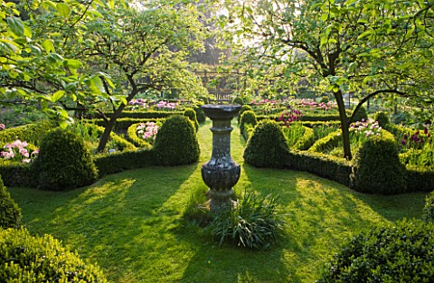 CERNEY_HOUSE_GARDEN__GLOUCESTERSHIRE_SUNLIGHT_SPARKLES_THROUGH_QUINCE_TREES_IN_THE_KNOT_GARDEN_IN_TH