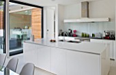 CAKE BOY HOUSE  LONDON: ALL WHITE STREAMLINED KITCHEN WITH ACCESS VIA SLIDING DOOR TO GARDEN