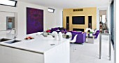 CAKE BOY HOUSE  LONDON: VIEW FROM KITCHEN TO THE INFORMAL DINING ROOM WITH TABLE  PURPLE SUEDE SOFA AND GOLD LEAF PAINTED MEDIA CENTRE ON THE BACK WALL IN THE MORNING ROOM