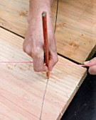 DESIGNER CLARE MATTHEWS - DECKING PROJECT - PENCIL MARKING OUT WHERE TO CUT DECK BOARDS