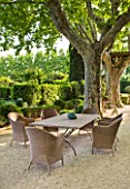 LES CONFINES  PROVENCE  FRANCE - DESIGNER: DOMINIQUE LAFOURCADE: THE GRAVEL TERRACE BESIDE THE HOUSE WITH PLANE TREES AND A TABLE AND CHAIRS - A PLACE TO SIT