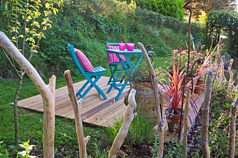 DECKING_PROJECT__DESIGNER_CLARE_MATTHEWS__WOODEN_DECK_WITH_BLUE_TABLE_AND_CHAIRS_AND_PINK_CUSHIONS