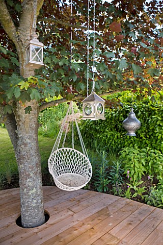 DECKING_PROJECT__DESIGNER_CLARE_MATTHEWS__DECK_WITH_HANGING_SEAT_AND_METAL_LANTERNS_HANGING_FROM_TRE