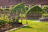 PRIEURE NOTRE-DAME DORSAN  FRANCE: THE CLOISTER - WOVEN WOODEN SEATS WITH QUINCE TREES TRAINED INTO HOOD-SHAPED ARBOURS