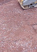 DESIGNER: CLARE MATTHEWS  DEVON - PAVING PROJECT - CLOSE UP OF SCALPING USED BENEATH PAVING BEING COMPACTED WITH A VIBRATING PLATE