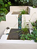 BARBARA KENNINGTON GARDEN  BRIGHTON: LOWER PATIO - WATER FEATURE WITH RENDERED BLOCK WALLS OF WARM IVORY - WATER TRICKLES DOWN A MOSAIC CHUTE INTO BASIN BELOW.