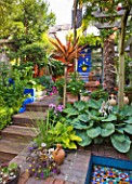 KARLA NEWELL GARDEN  BRIGHTON:  WOODEN STEPS LEAD DOWN FROM THE TERRACE BY THE HOUSE TO THE PERGOLA  MOSAIC POND  HOSTAS