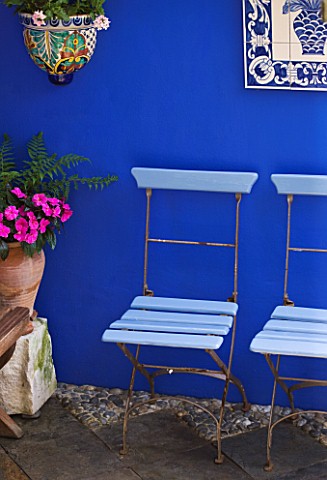 KARLA_NEWELL_GARDEN__BRIGHTON_SMALL_TOWN_GARDEN__BLUE_CAFE_CHAIRS_BESIDE_BLUE_PAINTED_WALL_WITH_CERA