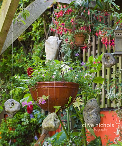 KARLA_NEWELL_GARDEN__BRIGHTON_SMALL_TOWN_GARDEN__ORANGE_WALL__HANGING_BASKETS_AND_STONES_GATHERED_FR