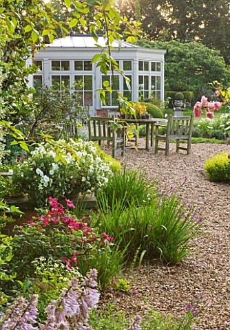 KINGSBRIDGE_FARM__BUCKINGHAMSHIRE_BORDER_ALONG_TERRACE_BY_HOUSE_AND_CONSERVATORY_WITH_TABLE_AND_CHAI