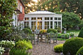 KINGSBRIDGE FARM  BUCKINGHAMSHIRE: BORDER ALONG TERRACE BY HOUSE AND CONSERVATORY PLANTED WITH BOX BALLS - TABLE AND CHAIRS - A PLACE TO SIT