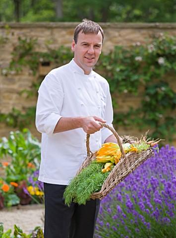 WHATLEY_MANOR__WILTSHIRE_HEAD_CHEF_MARTIN_BURGE_WITH_A_TRUG_FILLED_WITH_VEGETABLES_IN_THE_KITCHEN_GA