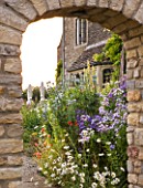 WHATLEY MANOR  WILTSHIRE: HERBACEOUS BORDER SEEN THROUGH ARCHWAY FROM THE KITCHEN GARDEN