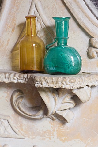 CHANTAL_COADY_HOUSE__LONDON_VINTAGE_BOTTLES_SIT_ON_A_LEDGE_ON_THE_OVERMANTEL_MIRROR_IN_THE_FIREPLACE