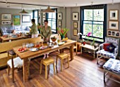 CHANTAL COADY HOUSE  LONDON: THE DINING ROOM WITH CHANTAL AND DAUGHTER MILLIE REFLECTED IN MIRRORED CUPBOARDS BEHIND. BALINESE TABLE