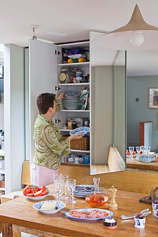 CHANTAL_COADY_HOUSE__LONDON_CHANTAL_AT_CONCEALED_STORAGE_CUPBOARD_WITH_MIRROR__IN_THE_KITCHEN