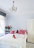 DESIGNER JACKY HOBBS  LONDON - WHITE BEDROOM AT CHRISTMAS WITH RED PILLOWS AND PRESENT ON BED