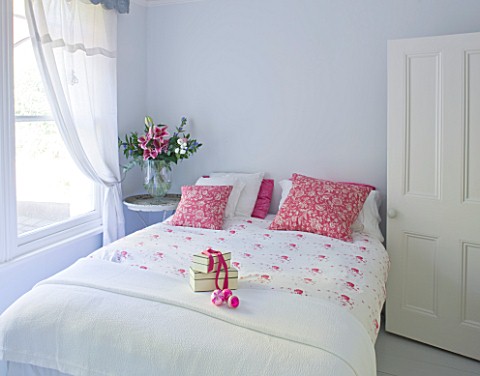 DESIGNER_JACKY_HOBBS__LONDON__WHITE_BEDROOM_AT_CHRISTMAS_WITH_RED_PILLOWS_AND_PRESENT_ON_BED
