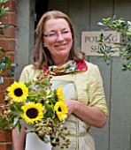 THE GARDEN AND PLANT COMPANY  HATHEROP CASTLE  CIRENCESTER  GLOUCESTERSHIRE: PATTIE WESTERN HOLDING FLOWER ARRANGEMENT OF BLACKBERRIES AND HELIANTHUS SUN RICH  AT THE NURSERY