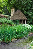 ASTHALL MANOR  OXFORDSHIRE: HERMITAGE BY THE POND BUILT OF AOK POSTS AND THATCH BY ISABEL BANNERMAN