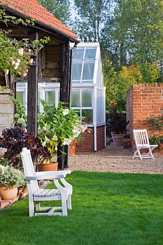 ULTING_WICK__ESSEX__THE_GARDEN_IN_AUTUMN__VIEW_TO_GREENHOUSE_WITH_WHITE_SEAT__CONTAINERS_PLANTED_WIT