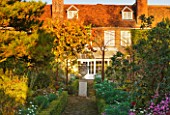 SALING HALL  ESSEX:  BRICK PATH LEADING TO HOUSE AND CONSERVATORY WITH URN ON PLINTH AND VINE IN AUTUMN COLOUR - EVENING LIGHT