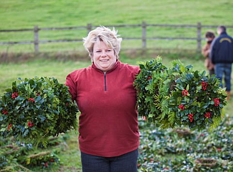 HOLLY_AND_MISTLETOE_AUCTION__TENBURY_WELLS__WORCESTERSHIRE__LADY_WITH_HOLLY_WREATHS_ON_ARMS