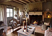 ROQUELIN  LOIRE VALLEY  FRANCE: SITTING ROOM - BEAMED CEILING  OPEN FIRE WITH VINTAGE FABRIC CANOPY  LINEN SHEET CURTAINS AND MISMATCHING VINTAGE SEATING