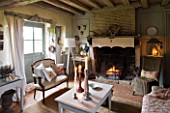 ROQUELIN  LOIRE VALLEY  FRANCE: SITTING ROOM - BEAMED CEILING  OPEN FIRE WITH VINTAGE FABRIC CANOPY  LINEN SHEET CURTAINS AND MISMATCHING VINTAGE SEATING