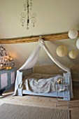 ROQUELIN  LOIRE VALLEY  FRANCE: BEDROOM; CANOPIED FRENCH PAINTED WOODEN BED WITH BEAMED CEILING AND PAPER LANTERNS