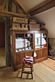 ROQUELIN  LOIRE VALLEY  FRANCE: SEWING ROOM; WOODEN BEAMS AND WOODEN FLOORING  VINTAGE GLASS CABINET HOLDS COLLECTIONS OF VINTAGE LINENS  WITH MORE IN BASKETS ON TOP