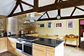 RICKYARD BARN HOUSE  OXFORDSHIRE: DESIGNERS JANE AND CLIVE NICHOLS. KITCHEN WITH BLACK MARBLE WORKTOP AND EXPOSED BEAMS