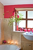 RICKYARD BARN HOUSE  OXFORDSHIRE: DESIGNERS JANE AND CLIVE NICHOLS. BATHROOM WITH TILES  PINK/ RED PAINTED WALL  SINK  CANDLES AND MISTLETOE - CHRISTMAS