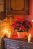 RICKYARD BARN HOUSE  OXFORDSHIRE: DESIGNERS JANE AND CLIVE NICHOLS. LIVING ROOM AT CHRISTMAS WITH CANDLES AND TERRACOTTA CONTAINER PLANTED WITH POINSETTIA