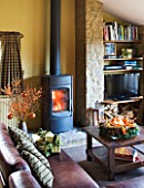 RICKYARD BARN HOUSE  OXFORDSHIRE: DESIGNERS JANE AND CLIVE NICHOLS. LIVING ROOM AT CHRISTMAS WITH CANDLE WREATH ON GLASS TOPPED COFFEE TABLE  LEATHER SOFAS  WOOD BURNING FIRE