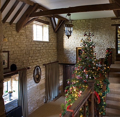 FULBROOK_HOUSE_GALLERIED_MAIN_HALL_WITH_CEILING_BEAMS__STONE_WALLS__WOODEN_STAIRCASE_DECORATED_TO_MA