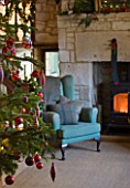 FULBROOK HOUSE: GALLERIED MAIN HALL WITH COTSWOLD STONE FIREPLACE  LOG BURNING STOVE AND LEATHER AND UPHOLSTERED ARMCHAIRS WITH CHRISTMAS TREE