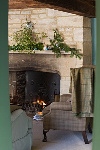 FULBROOK_HOUSE_SITTING_ROOM_WITH_BEAMED_CEILING__COTSWOLD_STONE_FIREPLACE_WITH_FURNISHINGS_IN_PLAID_