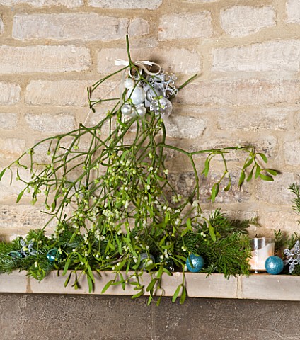 FULBROOK_HOUSE_SITTING_ROOM__STONE_MANTELPIECE_DRESSED_WITH_BOUQUET_OF_MISTLETOE_FOR_CHRISTMAS