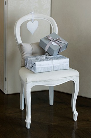 WHITE_HOUSE_FAMILY_ROOM__PAINTED_WHITE_WOODEN_DINING_CHAIR_WITH_SILVER_GIFT_WRAPPED_PRESENTS