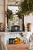 SARAH BAKERS HOUSE  THE OLD VICARAGE: DINING ROOM : DECORATIVE MANTLEPIECE WITH FRENCH FRAMED MIRROR  STONE BAULAUSTRADE CANDLE HOLDERS AND SEASONAL FRUIT AND FLOWER DISPLAYS.